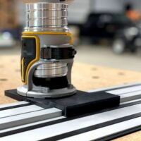 Dewalt router adapter mounted on Dewalt guide rail track, showing black base plate attached to aluminum rail