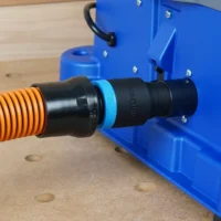 Black ToolCurve 1-1/4" hose adapter joining an orange hose to the rear dust port of a blue Kreg Foreman