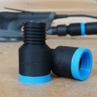 Two black hose adapters with blue knurled grip rings, one showing threaded male end and one showing female port, displayed on a workbench