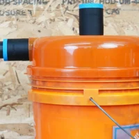 Two black ToolCurve 1-7/8 inch hose adapters with blue rings on a Dustopper separator lid, one with hose attached
