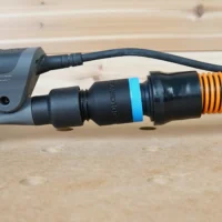 Black ToolCurve 1-1/4 inch hose adapter with blue band joining a 3M Xtract sander's dust port to an orange hose