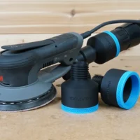 Black ToolCurve 2-1/2" hose adapter with blue ring beside a 3M Xtract sander, second adapter on hose