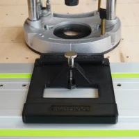Black LR 32 adapter plate with brass knob mounted on Festool guide rail below Dewalt 625 router base