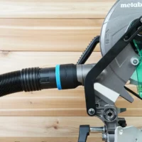 Black ToolCurve 2-1/2 inch hose adapter with blue band joining a ribbed hose to a Metabo HPT miter saw dust port