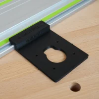 Black plastic guide rail adapter mounted on a Festool track saw rail, with a circular opening visible on the flat base