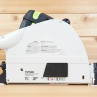 White arbor dust cover installed on Festool TS 75 track saw, showing snap-on design and safety warnings on blade guard