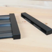 Two black protective caps for Ridgid track saw rails, one attached to the rail and one displayed separately on wood surface