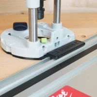 White plastic guide rail adapter mounted on Festool 1400 router, attached to aluminum guide rail on workbench