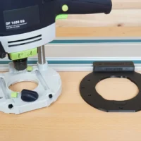 Black guide rail adapter shown alone and mounted on a Festool 1400 plunge router above a wooden work surface