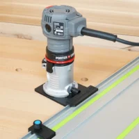 Porter Cable trim router mounted on black rail adapter, positioned over Festool guide rail on wooden workbench