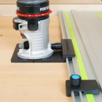 ToolCurve Porter Cable trim router rail adapter mounted on router base plate and attached to a guide rail on wood