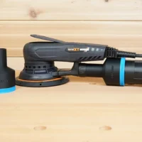 Black ToolCurve 2-1/2 inch hose adapter with blue band beside a MAXXT sander with a second adapter fitted to its rear dust port