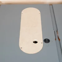Cream MDF zero clearance insert installed in a Craftsman 10-inch table saw top, showing oval shape with center blade slot and mounting holes