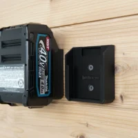 Two black Makita 40V wall mounts screwed to pine boards, one holding a BL4040 XGT battery, one empty