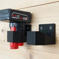 Two black M12-marked battery mounts screwed to a wood wall, one holding a Milwaukee M12 XC4.0 battery