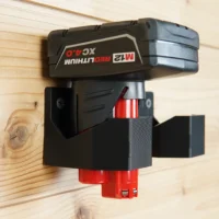Black battery holder mount with red base, mounted on wood wall with Milwaukee 12v battery inserted and secured