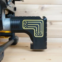 Black plastic bucket adapter with yellow-outlined dust routing diagram, mounted on rear port of DeWalt table saw