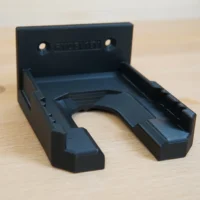 Black wall-mount battery holder for Ryobi 18v battery, shown from above with mounting holes visible