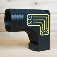 Black plastic DeWalt table saw dust collection adapter with yellow printed circuit diagram, cylindrical port on left side, bucket hanging slot below