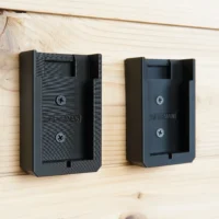 Two black Craftsman 20v battery mounts mounted on light wood, each with two Phillips screws visible and a slot for battery insertion