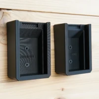 Two black plastic battery mounts mounted on wood wall, each with screw holes and internal guides sized for Ryobi 40V batteries