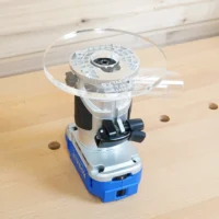 Clear 6-inch round acrylic router base plate mounted on a blue Kobalt trim router on a workbench