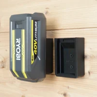 Two black Ryobi 40V battery wall mounts screwed to pine boards, one holding a 4Ah battery, one empty