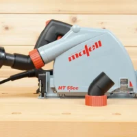 ToolCurve No Snag Dust Port adapter attached to a Mafell MT 55cc track saw, with vacuum hose connected, angling upward on light wood surface