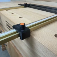 Black plastic parallel guide with orange knob mounted on brass Incra T-Track rail attached to Ridgid track saw guide rail