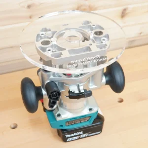 Clear 8-inch round acrylic router base plate marked Makita Trim Plunge, mounted on a Makita cordless plunge router
