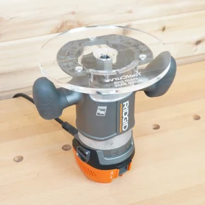 Clear 8-inch round acrylic router base plate mounted on a Ridgid 2 HP fixed base router, viewed from above