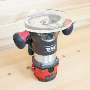 Clear 8-inch round acrylic router base plate marked Skil Fixed Base, mounted on an inverted Skil router