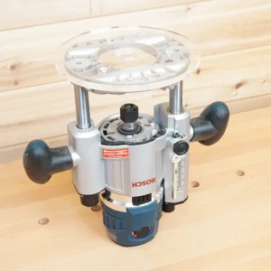 Clear 8-inch round acrylic router base plate mounted on an upside-down Bosch MR23EVS plunge router