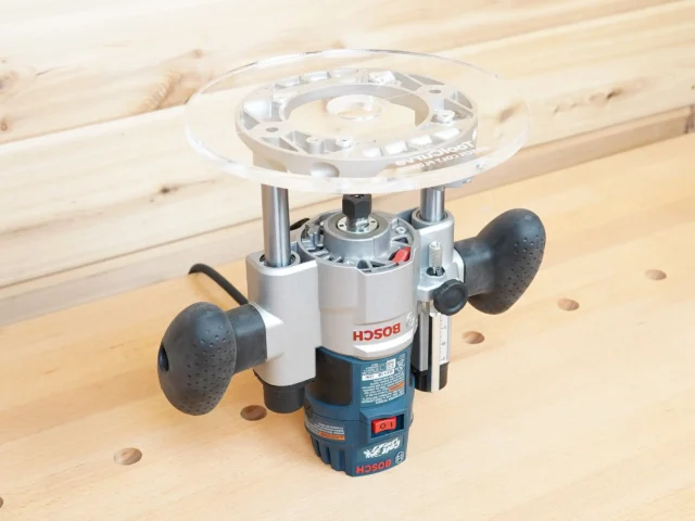 8-inch acrylic router base plate mounted on a Bosch plunge router, showing the clear round platform and guide bushing opening from above
