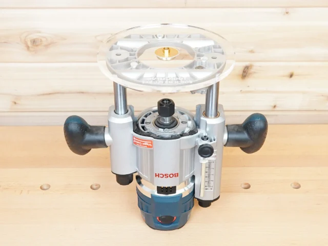 8-inch clear acrylic router base plate attached to Bosch MR23EVS plunge router, shown from above on wood surface
