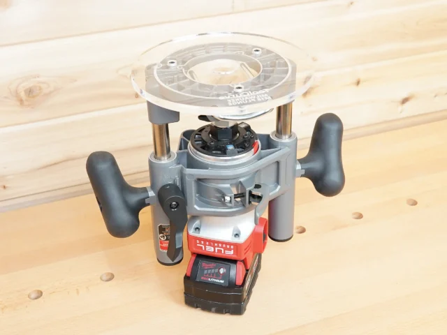 8-inch clear acrylic router base plate mounted on a Milwaukee M18 2-1/4HP router, showing wide circular platform and dual handles