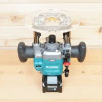 8-inch clear acrylic router base plate mounted on a Makita 40v cordless router, shown from above on a wooden workbench